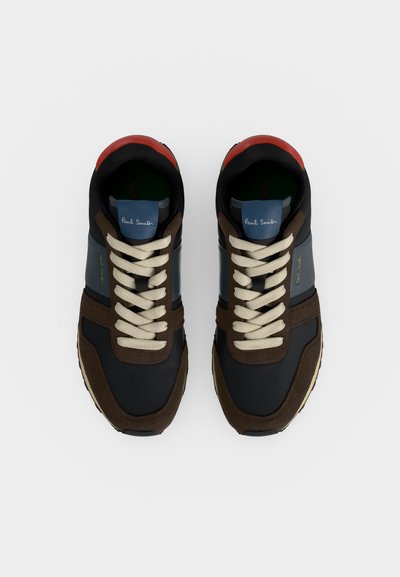 Paire de baskets noires, marron et bleues avec des lacets beiges et des accents rouges au talon, vue de dessus sur fond blanc.
