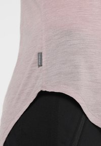 Ljusrosa kortärmad skjorta i mjukt tyg, med en rundad nederkant och en liten svart etikett på sidan.