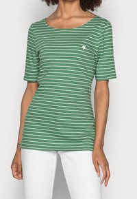 Camiseta verde a rayas con cuello redondo, mangas cortas y rayas horizontales blancas; cuenta con un pequeño logo en el pecho.