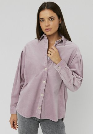 Chemise en velours côtelé lavande clair avec une fermeture à boutons, des manches longues et une coupe décontractée. Dotée d'un col classique et de nervures verticales visibles.