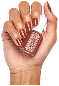 Brauner Nagellackflasche mit einem weißen Deckel, die in einer Hand gehalten wird, wobei die gepflegten Nägel in derselben Farbe lackiert sind. Glatte Textur.