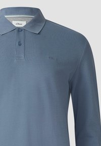 Lange mouwen polo-shirt in lichtblauwe textuurstof. Beschikt over een klassieke kraag, een placket met drie knopen en een reliëflogo van het merk op de borst.