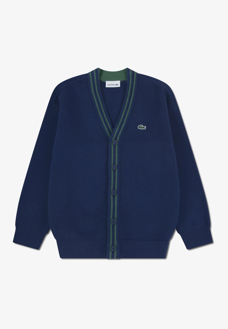 Cardigan bleu marine boutonné avec bordure rayée vert foncé, manches longues, poignets en côtes et petit logo crocodile vert sur la poitrine gauche.