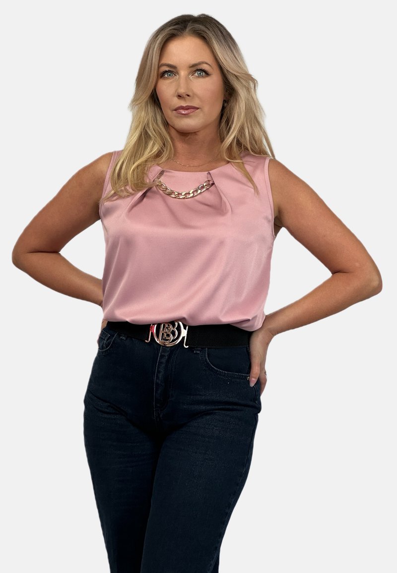 Różowa satynowa bluzka bez rękawów z fałdami, ozdobiona złotym łańcuszkiem. Noszona z ciemnymi dżinsami z wysokim stanem oraz paskiem z metalową klamrą.