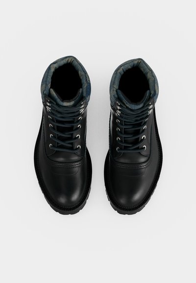 Paire de bottes en cuir noir à lacets avec col matelassé bleu à motifs, vues du dessus sur fond blanc.
