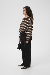 Brown and cream-striped long-sleeve shirt, black high-waisted flared jeans, black pointed toe shoes, holding a small black handbag.