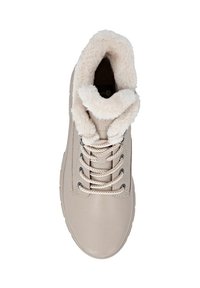 Beżowe skórzane trampki z miękkim, kremowym futrzanym kołnierzem, okrągłymi sznurowadłami i metalowymi oczkami, posiadające fakturowaną cholewkę i płaską podeszwę.