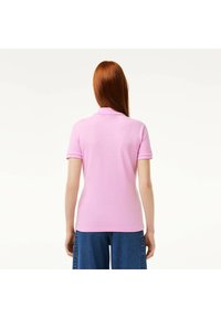 Polo shirt rosa con colletto classico, maniche corte e design aderente, realizzato in cotone morbido. Nessun motivo visibile.