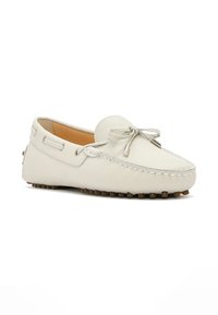 Zapato mocasín de cuero blanco con punta redonda, lazo decorativo y costuras en contraste; presenta protuberancias de goma en la suela para mayor agarre.