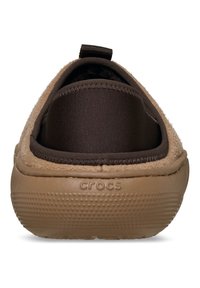 Brązowe buty wsuwane z futrzanym wierzchem, elastycznymi bocznymi panelami oraz teksturowaną beżową podeszwą z logo "CROCS".