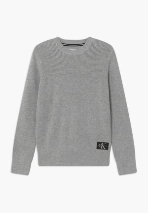 Maglione grigio a maglia con scollatura rotonda, polsini e orlo a coste, caratterizzato da una patch nera con logo sul lato sinistro in basso.