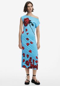 Kék, váll nélkül viselhető ruha, nagyméretű piros rózsanyomattal és szétszórt piros pétaljakkal. Simogató anyagból készült, testhezálló fazon.