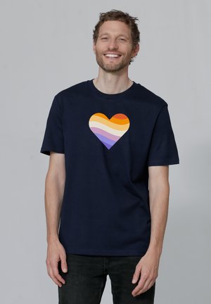 Navyblauwe katoenen t-shirt met een hartontwerp in een gradient van oranje, paars en geel, korte mouwen en een ronde hals.
