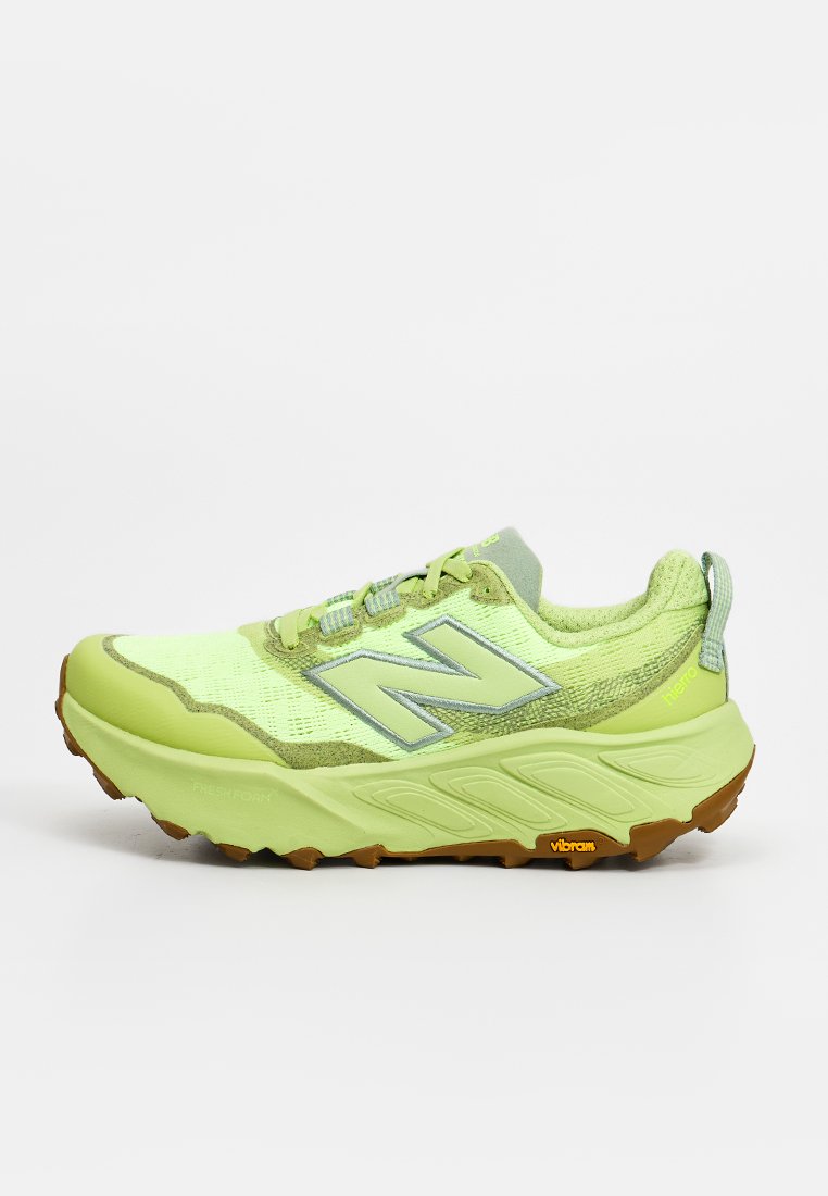 Zapatilla deportiva New Balance de color verde claro con suela gruesa, parte superior de malla y suela Vibram, vista desde el lateral izquierdo sobre fondo blanco.