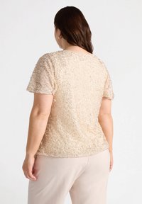 Harmaa lyhythihainen paita, jossa on tekstuuritaitoksia ja pehmeä, epäsäännöllinen kuvio. Takana on sileä pinta ja pyöreä kaula-aukko.