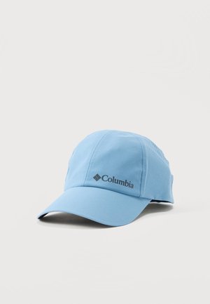 Lyseblå Columbia baseballcap med buet skygge og logo foran, der hviler på en hvid overflade.