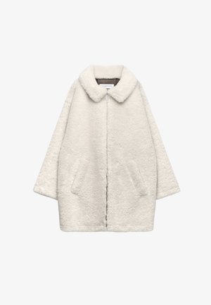 Manteau en fausse fourrure plush écru avec un large col, fermeture éclair, manches longues et deux poches avant, présenté sur un fond blanc.