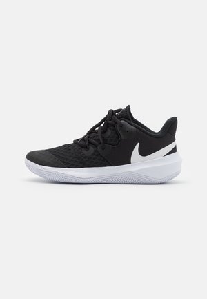 Sapatos atléticos pretos feitos de malha e materiais sintéticos, apresentando um logo swoosh branco, design com atacadores e sola de borracha texturizada.