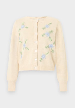 Kreemikas kudumiga kardigan pikkade varrukate, ees nuppudega ja hele sinise lille tikandiga roheliste lehtedega ees mõlemal küljel.