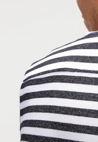Gestreepte shirt met witte en donker marineblauwe horizontale strepen, met een subtiele textuur en een ronde halslijn, waarin de rekbaarheid van de stof zichtbaar is.
