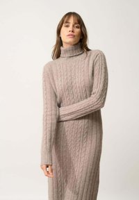 Vestito a collo alto lavorato a maglia in rosa chiaro, con un motivo a trecce, maniche lunghe e polsini a coste. Texture morbida con una silhouette aderente.