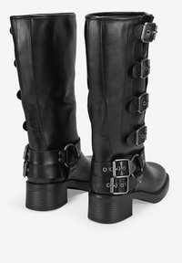 Botas de cuero negro hasta la rodilla con cinco hebillas decorativas en el lateral, punta redonda, suela texturizada y sólido tacón cuadrado.