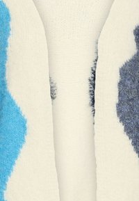 Cardigan lavorato a maglia con grandi motivi astratti blu e blu scuro su uno sfondo crema. Tessuto morbido con un design aperto davanti.