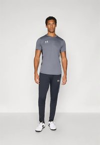 Γκρίζα αθλητική μπλούζα με κοντά μανίκια, συνδυασμένη με ναυτικές στενές φόρμες. Λευκές λεπτομέρειες λογότυπου και στα δύο κομμάτια και λευκά υποδήματα.