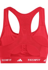 Sujetador deportivo atlético rojo con diseño de espalda nadadora, hecho de tejido texturizado, que presenta un logo blanco "TECHFIT" a lo largo de la banda elástica.