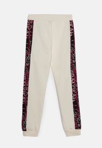 Lys beige sweatpants med pink og sort leopardprint på siden. Lavet af blødt stof, med elastisk waistband og manchetter.