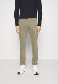 Chinos i ljusbeige bomull med slim fit. Uppvikta muddar och sidofickor. Matchas med vita sneakers och en marinblå rundhalsad tröja.