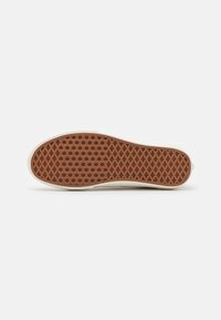 Brown rubber shoe sole with a geometric pattern, beige edges, and a smooth surface. Texture designed for grip and durability.