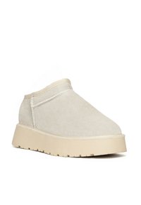Zapato de ante beige hasta el tobillo con punta redonda, acentos de costura sutil y suela de goma texturizada, diseñado para la comodidad y el uso informal.