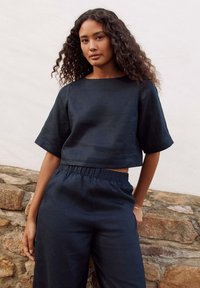 Cropped dark navy linen top with short sleeves paired with matching wide-leg pants, featuring an elastic waistband and simple design.
