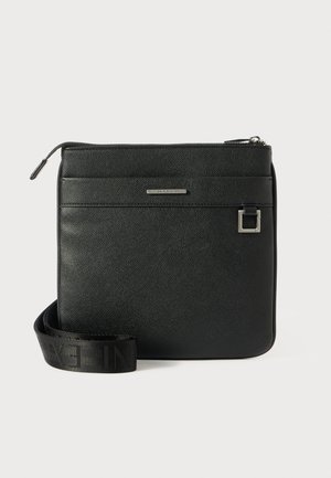 Mustmust kott, mis on valmistatud tekstuurilisest sünteetilisest materjalist. Omab lukk sulgemist, esipoolt ja reguleeritavat rihma brändimisega.