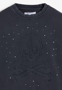 Sudadera negra con diseño de calavera y huesos cruzados bordado, decorada con pequeños remaches metálicos dispersos alrededor del gráfico.