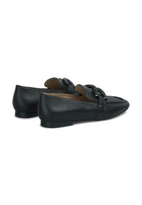 Zwarte leren loafers met een platte hak, voorzien van een strapaccent en een gladde textuur. Ronde teen met lichte detaillering op de wreef.