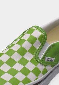Slip-on παπούτσι Vans με μοτίβο πράσινου και λευκού καρό, λευκή σόλα και εμφανή ετικέτα με το λογότυπο Vans στο πλάι.