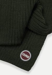Fular tricotat de culoare verde închis, cu o textură ribbed. Are un logo circular brodat în burgundy și argintiu într-unul din colțuri.