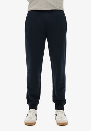 Marineblauwe joggerbroek van een katoenmix, met een trekkoord in de taille, zijzakken en geribbelde boorden. Gecombineerd met witte sneakers.