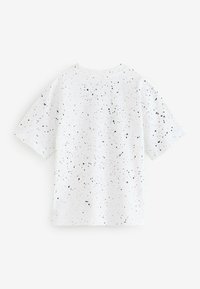 Hvid t-shirt med en afslappet pasform, der har et broget sort mønster over hele overdelen. Korte ærmer og rund halsudskæring. Lavet af bomuldsmateriale.