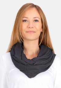 Schwarzer Infinity-Schal aus weichem, strukturiertem Stoff, mit einem geschichteten Design, das sich um den Hals legt. Wird über einem weißen Oberteil getragen.