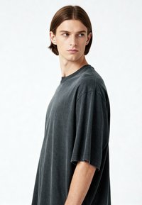 Per didelės apimties crew-neck marškinėliai tamsiai pilkos spalvos iš medvilnės. Savybės - trumpi_rankoviai su neapdirbtu apvadu ir švelnus, šiek tiek tekstūruotas paviršius.