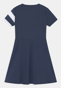 Marinblå klänning med kort ärm och utsvängd kjol. Har vita och marinblå ränder på ärmarna. Tillverkad av mjukt, elastiskt tyg.