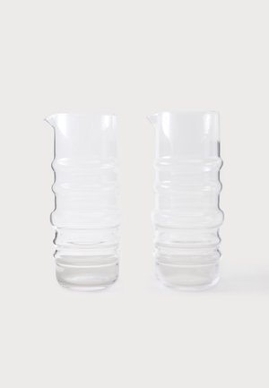 To klare glas-kander med ribbet tekstur og små tud, stående side om side på en hvid baggrund.