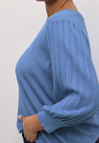 Pull tricoté bleu clair avec détails côtelés sur les épaules et les manches, coupe décontractée et texture douce.