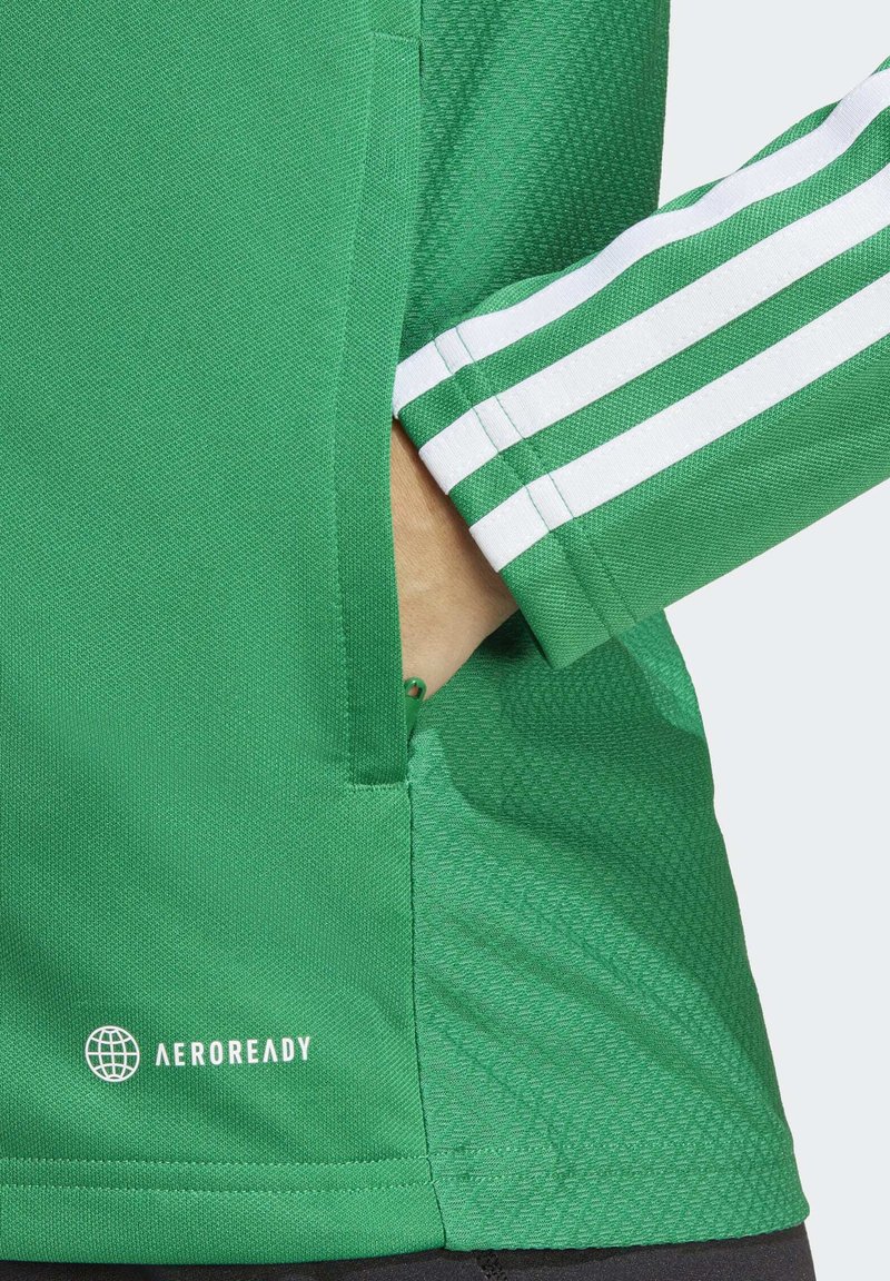 Zielona koszulka sportowa z teksturowanej tkaniny, kieszonką po bokach i białymi paskami na rękawie. Posiada logo "AEROREADY" w kolorze białym.
