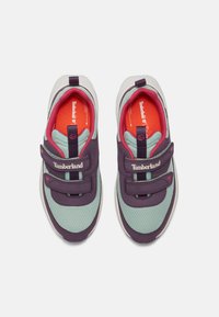 Lila och mintfärgade sneakers med nätövre, kardborrestängning och röd insida. Har Timberland-logotyp på sidan. Förstärkt tåparti.