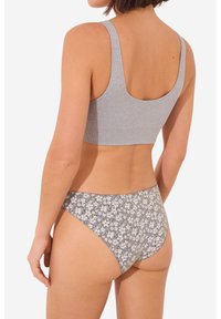 Grijze geribbelde bralette met brede banden, gecombineerd met een hooggeknipte onderkant met een licht bloemenpatroon op een donkere achtergrond.