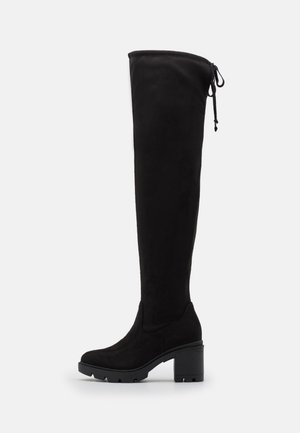 Botte noire mi-mollet avec talon épais, bout arrondi, semelle crantée et lien ajustable à l'arrière en haut.